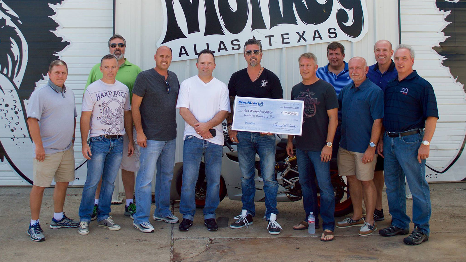 Gas Monkey Foundation team holding a big check in front of their garage