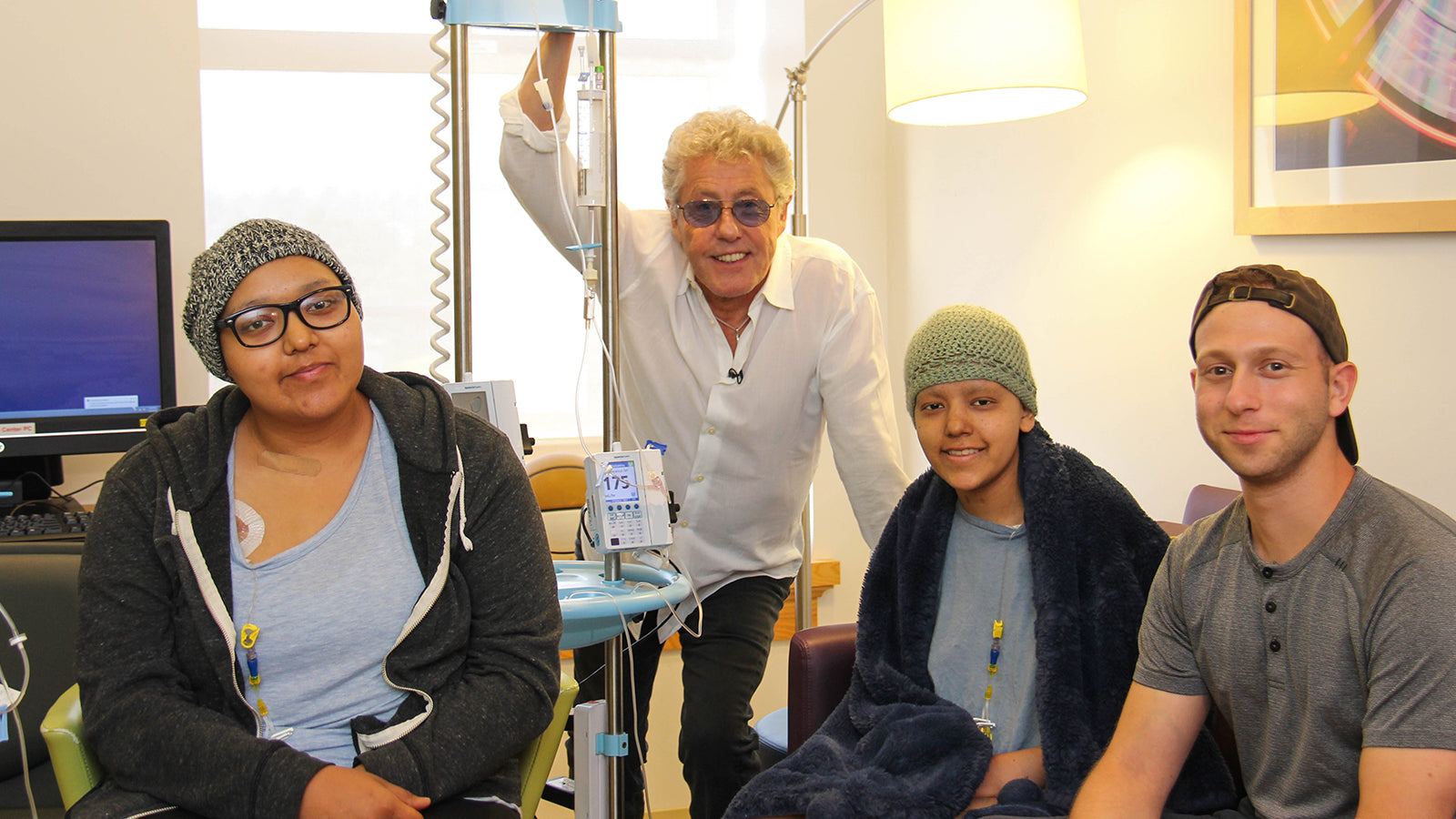 Roger Daltrey of The Who smiles with three teenage cancer patients