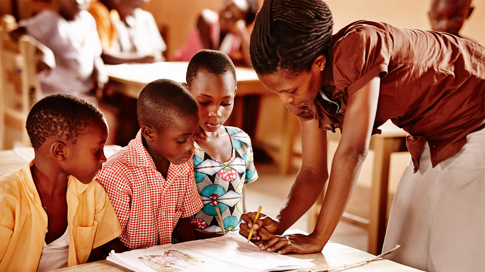 A teacher educating a group of three children in a Ghana classroom