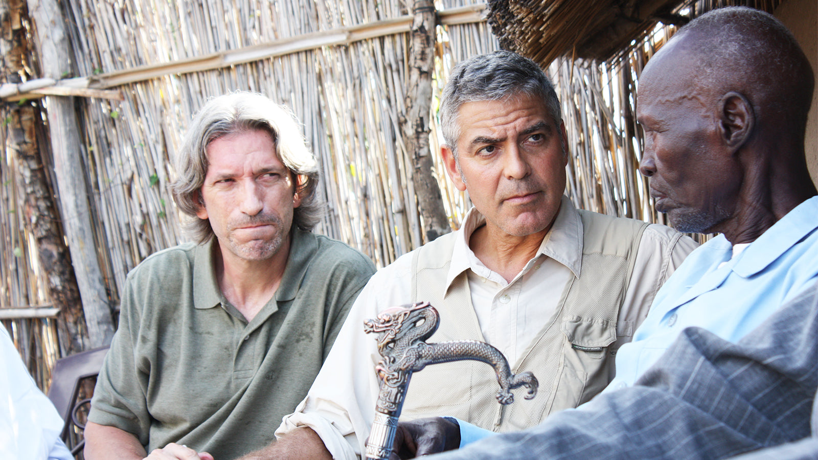 George Clooney sits and speaks with two men.