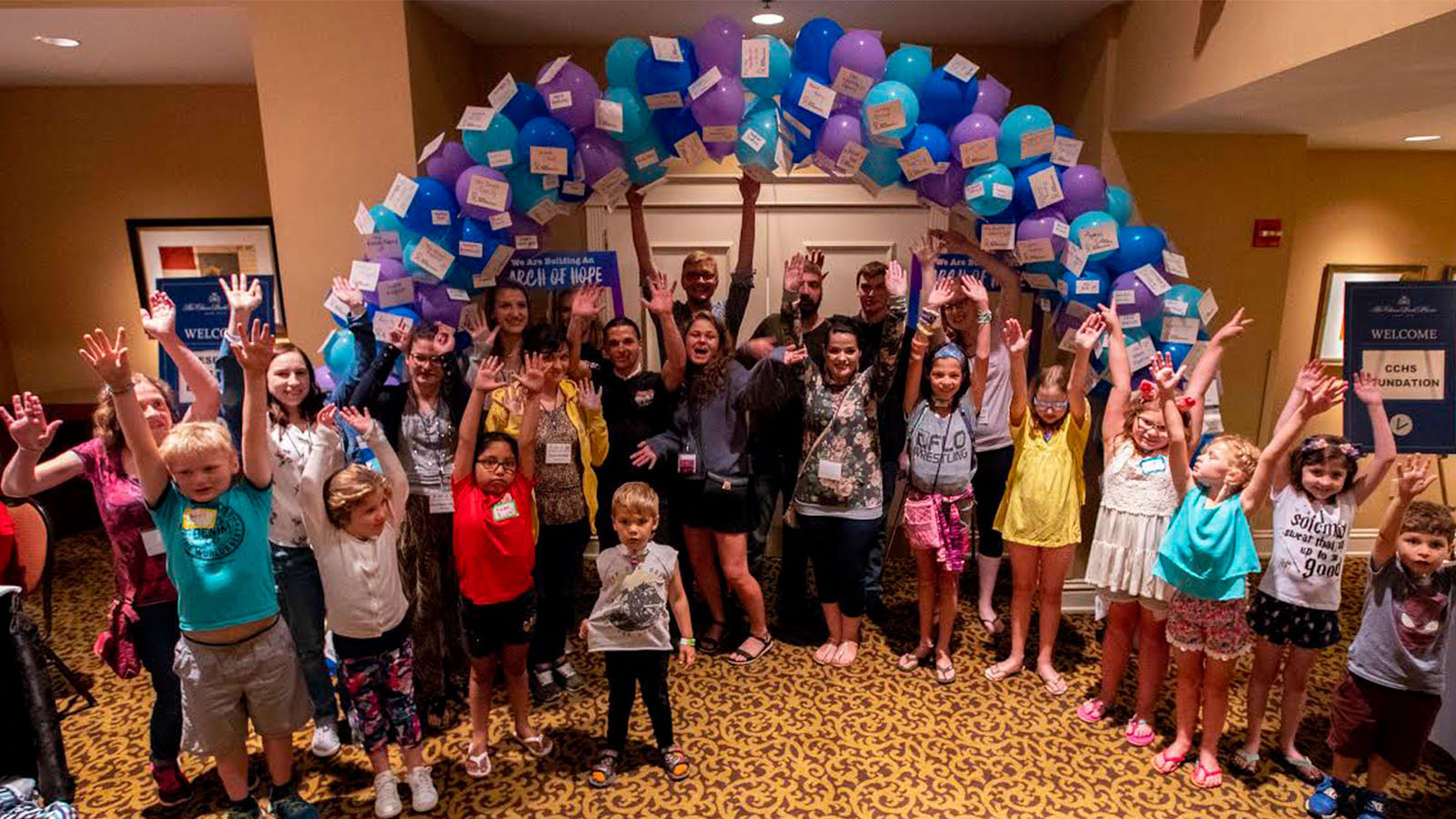A group of children with CCHS celebrate under an archway of balloons