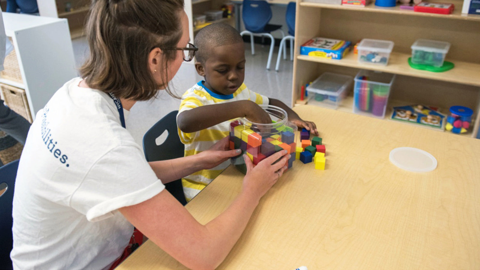 A NEXT for Autism volunteer and child play with legos